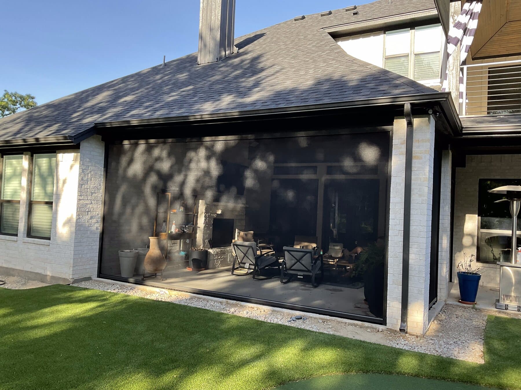 Full-width dark motorized screen installed on a residential patio